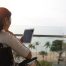 Handicapped person or patient sit on wheelchair using tablet at balcony of hotel at beachside